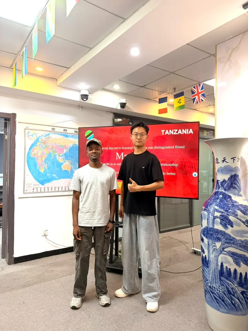 Two colleagues in a supplier office beside a world map and Tanzania banner